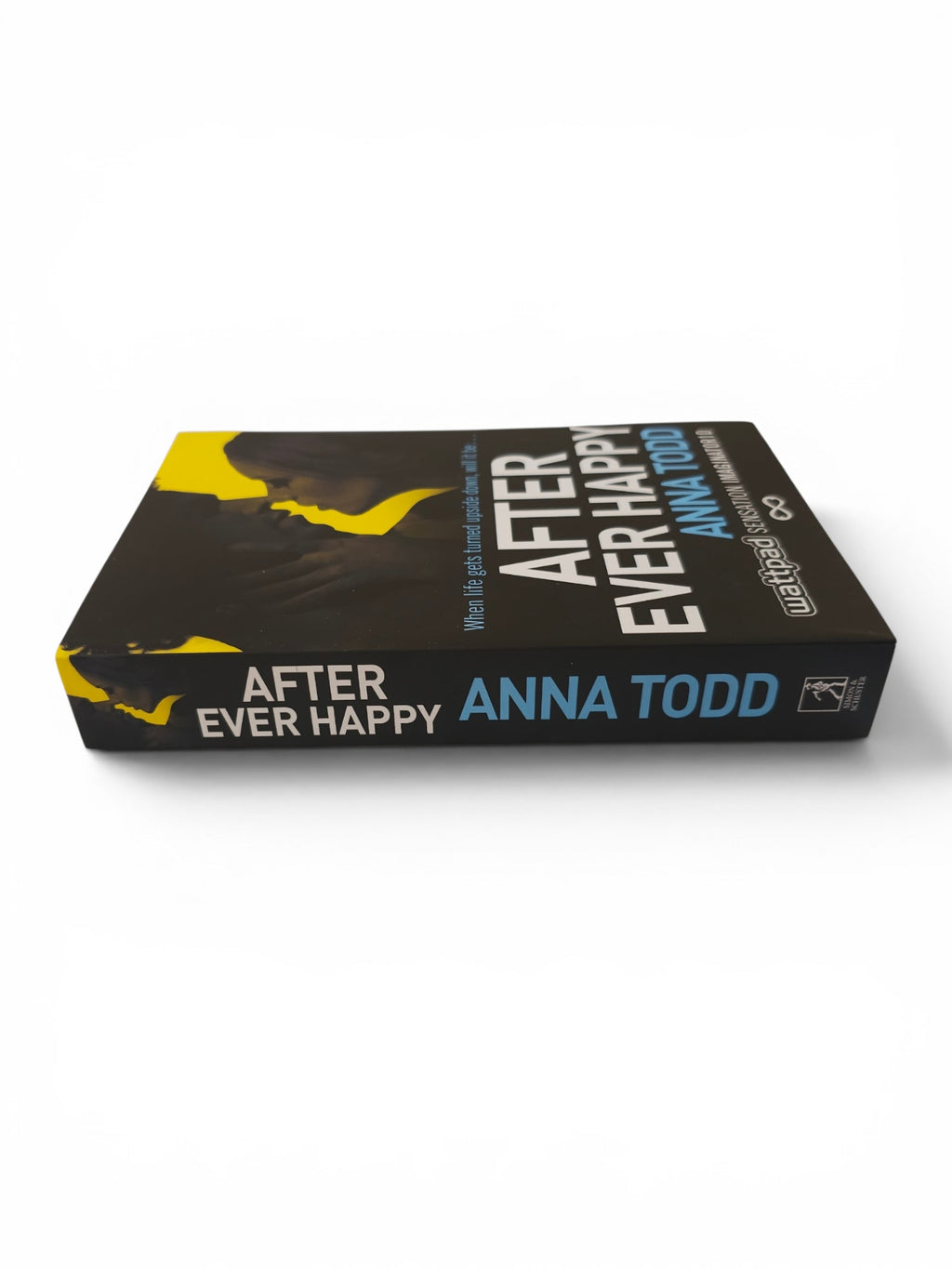 A paperback book titled 'After Ever Happy' by Anna Todd, shown at an angle on a clean white background. The cover is predominantly black with yellow graphic accents and white and blue text.