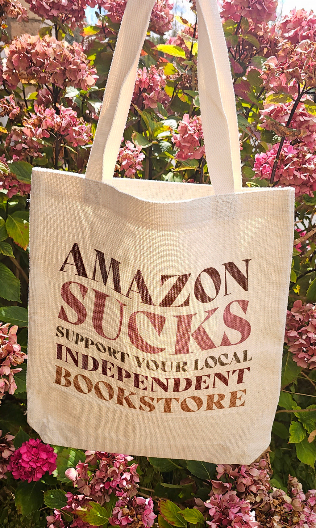 A tote bag featuring 'Amazon sucks, support your local independent bookstore'