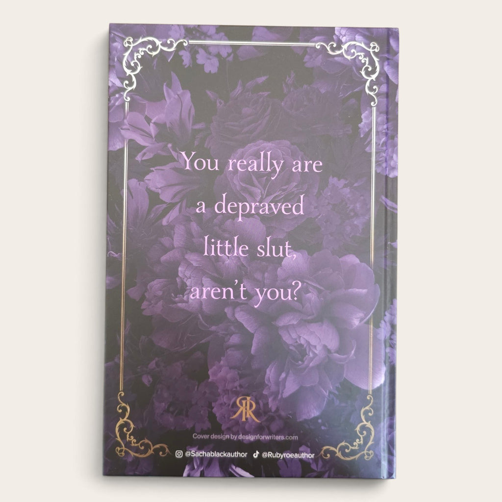 A book cover featuring a purple floral background with a quote in light purple text: 'You really are a depraved little slut, aren't you?' Ornate silver and gold decorative borders frame the cover, and a small monogram logo with social handles appears at the bottom.