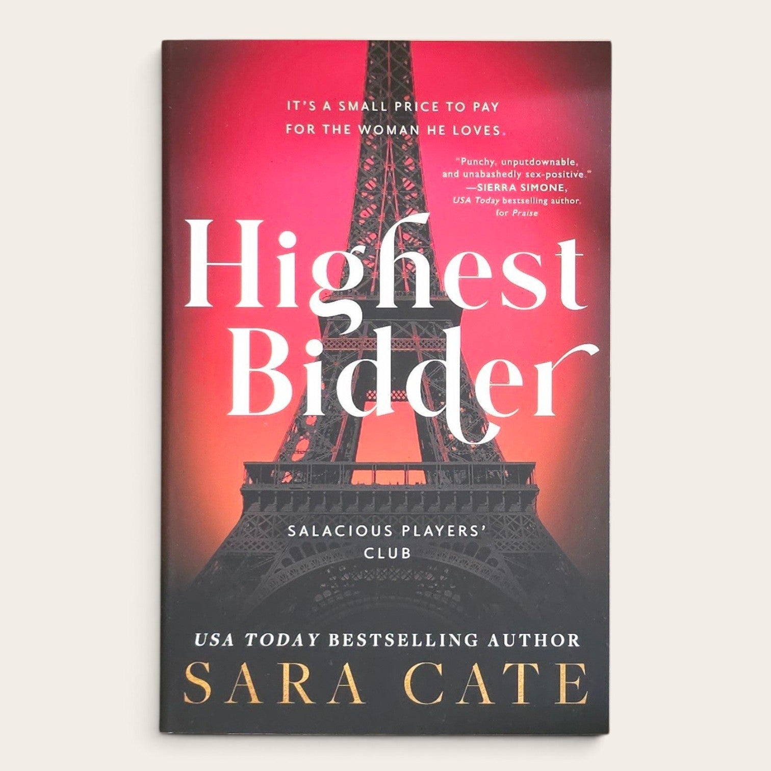 Book cover of 'Highest Bidder' by Sara Cate, featuring a red and black gradient background with a large Eiffel Tower silhouette and white title text.