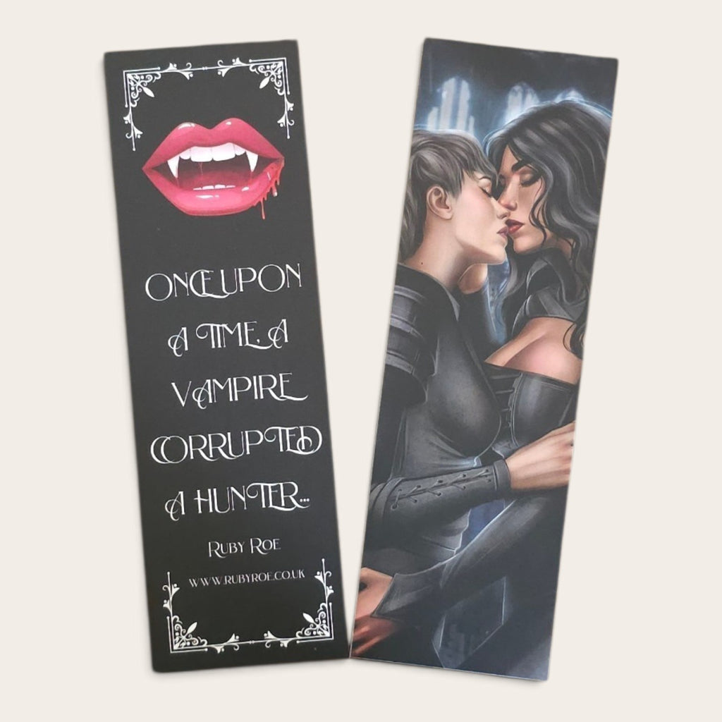 Two printed bookmarks shown on a light beige background. The left item is black with a graphic of vampire lips and white gothic text reading 'Once upon a time a vampire corrupted a hunter' plus 'Ruby Rose' and a website.