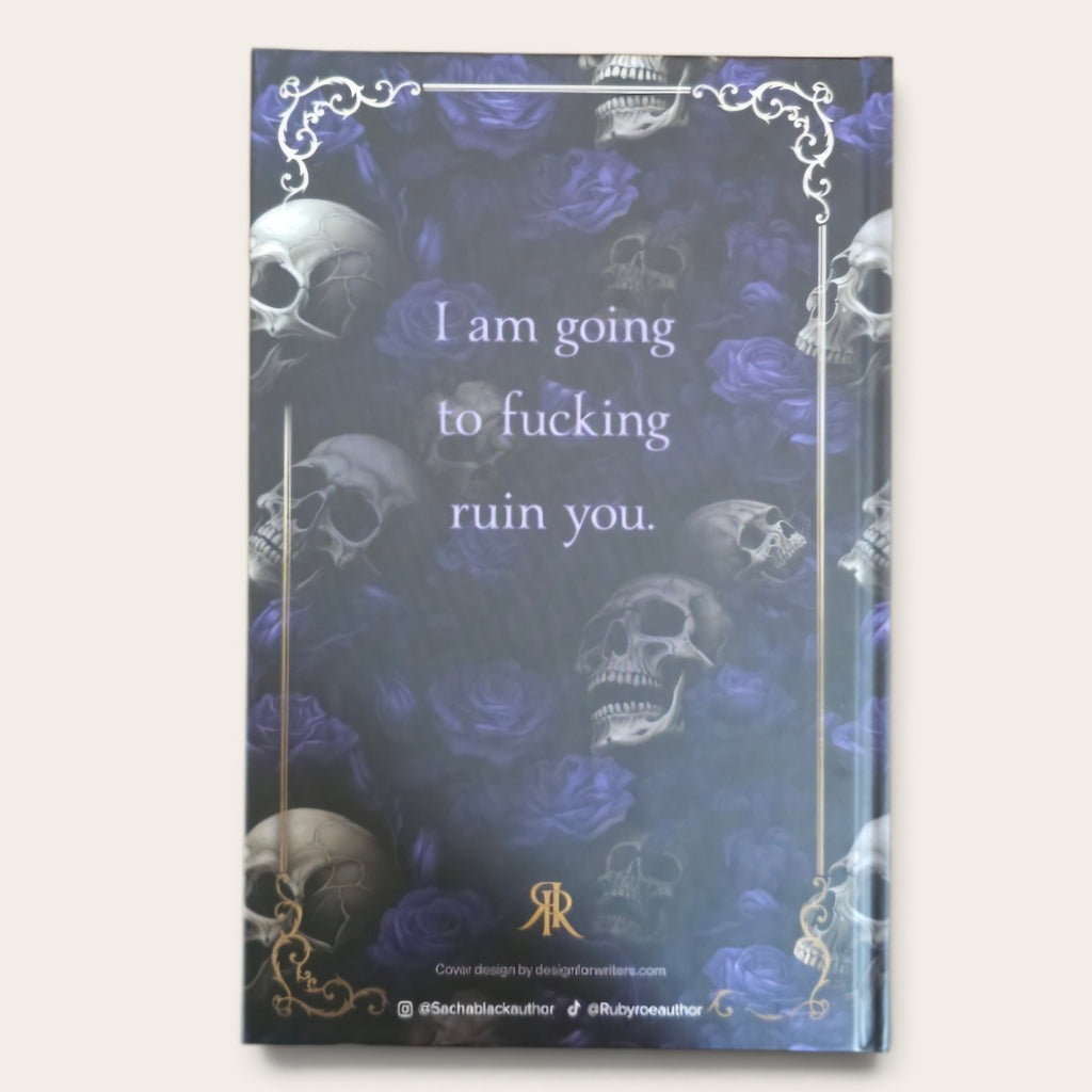 A hardcover book with a dark gothic cover design featuring skulls and purple roses, with the text 'I am going to fucking ruin you.' in white, framed by ornate gold corner flourishes.