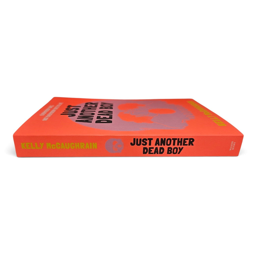 A hardcover book titled 'Just Another Dead Boy' by Kelly McLaughlin, featuring a bright orange-red cover with a stylized skull graphic and black and yellow text, shown on a plain white background.