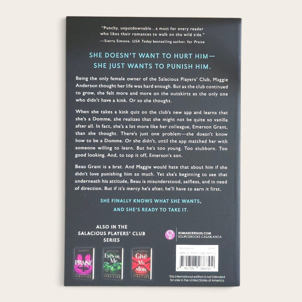 The back cover of the book Mercy by Sara Cate, displayed against a light beige background. The cover is dark gray with white text and features book series logos at the bottom.