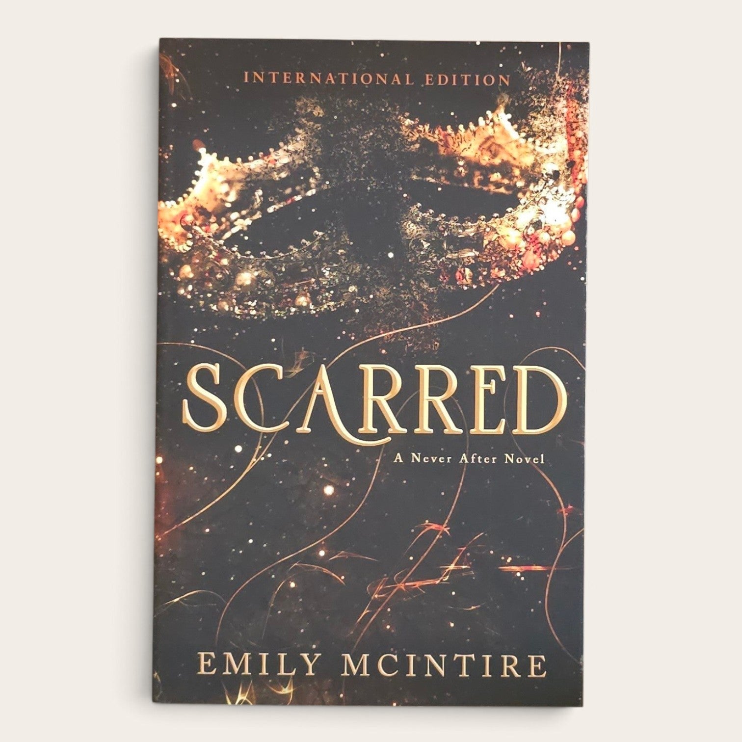 The front cover of the book 'Scarred: A Never After Novel' by Emily McIntire, shown as an International Edition paperback against a light beige background.