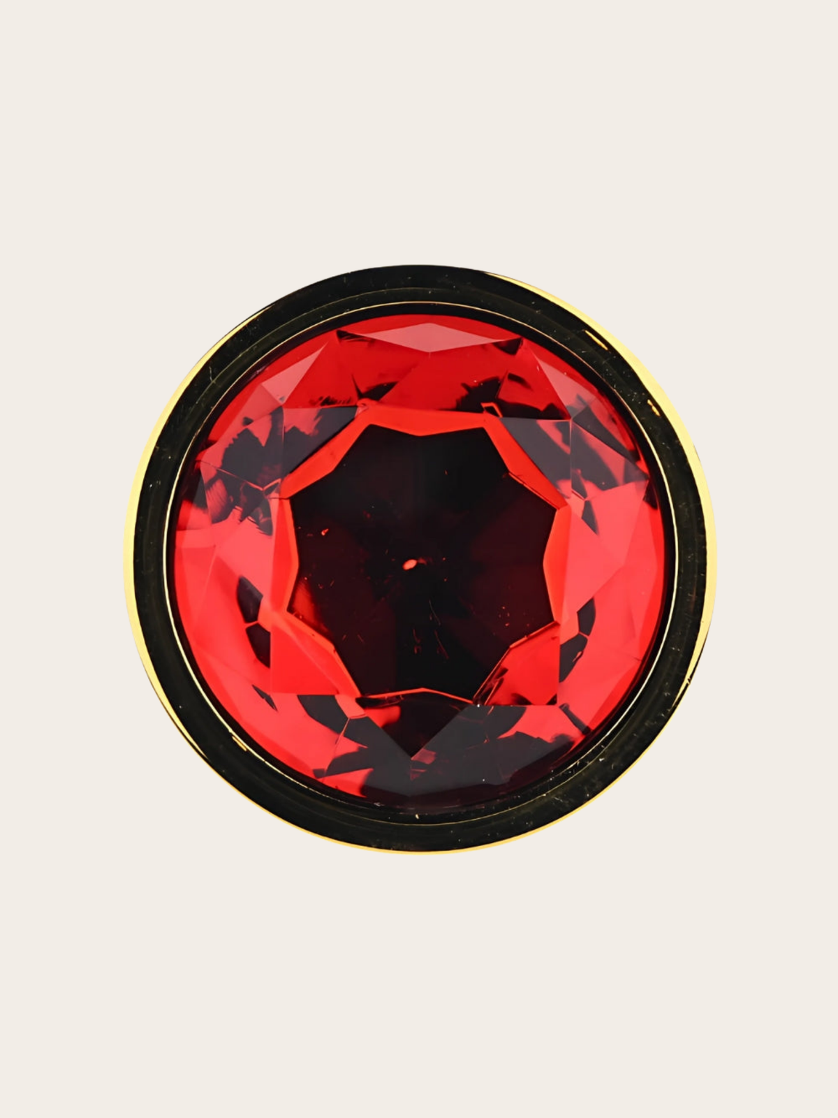A round red faceted gemstone or decorative jewel with a thin gold edge, centered on a light beige background.