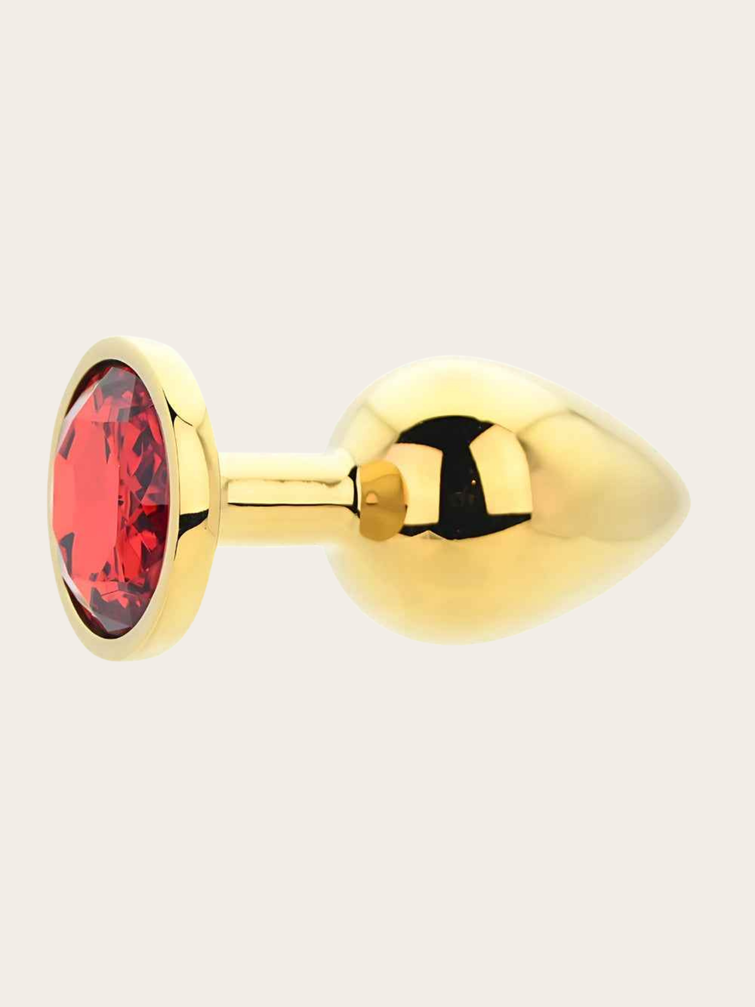 A gold butt plug with a faceted red gemstone set in a gold bezel, shown from a side profile on a light beige background.