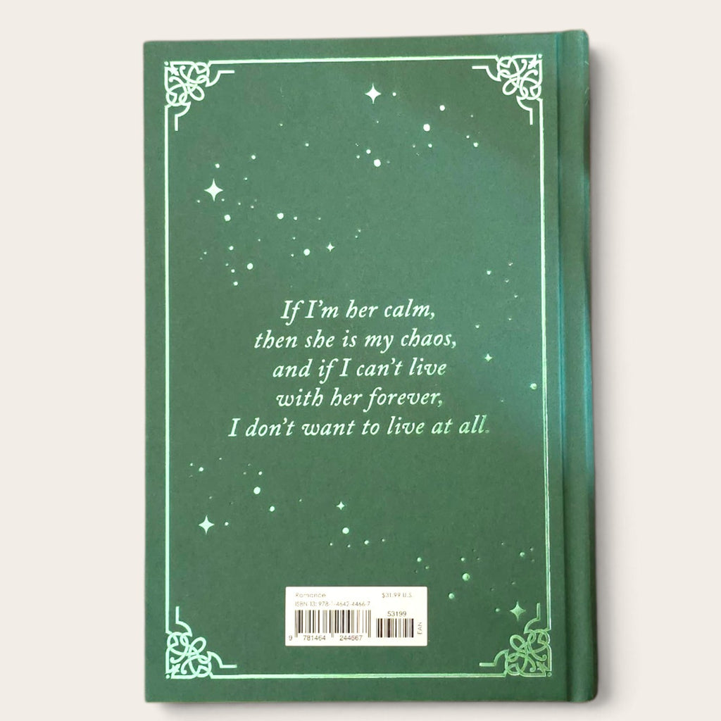 A green hardcover book shown from the back, featuring a decorative border, script text with a quote, and a barcode label near the bottom, photographed against a light beige background.